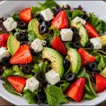 Ensalada saludable con aguacate, fresas, queso feta, aceitunas negras y hojas verdes frescas