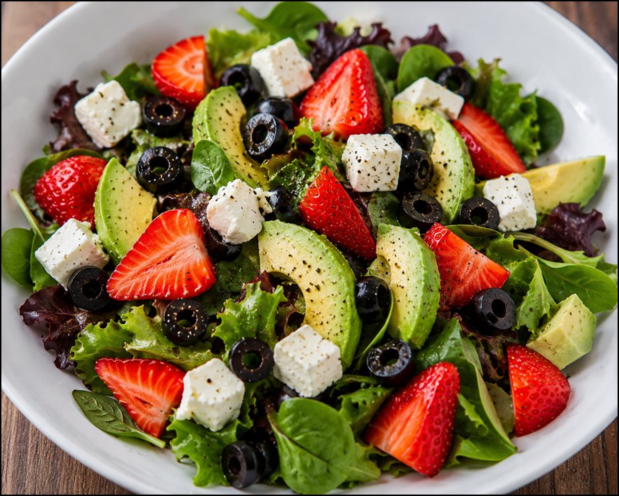 Ensalada saludable con aguacate, fresas, queso feta, aceitunas negras y hojas verdes frescas