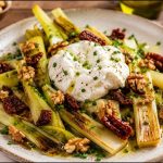Puerros asados con burrata cremosa, nueces y tomates secos aliñados con aceite de oliva